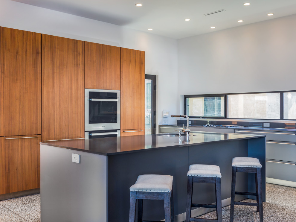 Moderne Küche mit Unterbauwaschbecken, flächenbündigen Schrankfronten, braunen Schränken, Küchengeräten aus Edelstahl, Terrazzo-Boden, buntem Boden und schwarzer Arbeitsplatte in Austin