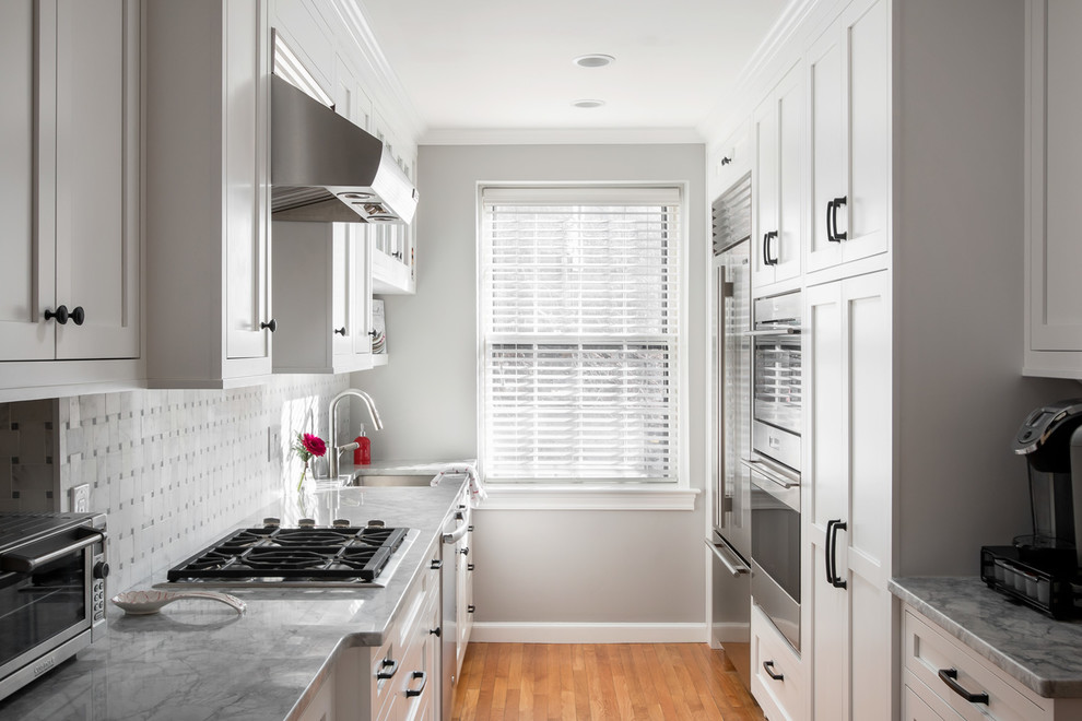 Eat-in kitchen - mid-sized transitional galley medium tone wood floor eat-in kitchen idea in Boston with an undermount sink, shaker cabinets, white cabinets, quartzite countertops, white backsplash, marble backsplash and stainless steel appliances