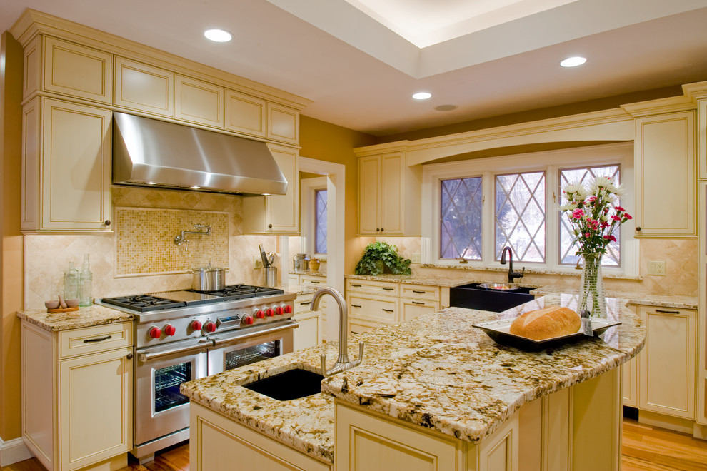 Bild på ett stort vintage kök och matrum, med en rustik diskho, luckor med infälld panel, gula skåp, granitbänkskiva, beige stänkskydd, stänkskydd i keramik, rostfria vitvaror och mellanmörkt trägolv