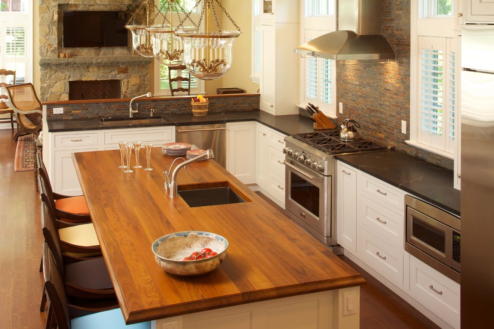 Inspiration for a large modern l-shaped medium tone wood floor eat-in kitchen remodel in New York with an undermount sink, recessed-panel cabinets, white cabinets, soapstone countertops, multicolored backsplash, stone tile backsplash, stainless steel appliances and an island