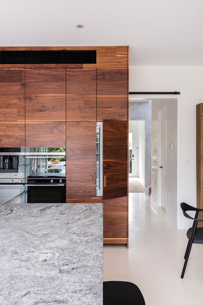 Design ideas for a large contemporary l-shaped open plan kitchen in Sydney with a submerged sink, medium wood cabinets, granite worktops, white splashback, black appliances, an island and white floors.
