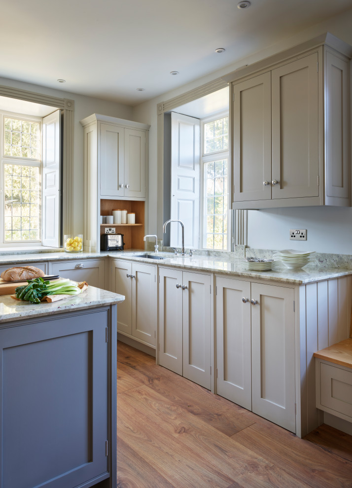 Inspiration pour une grande cuisine américaine traditionnelle avec un évier intégré, un placard à porte shaker, un plan de travail en granite, une crédence grise, un électroménager noir, îlot et un plan de travail blanc.