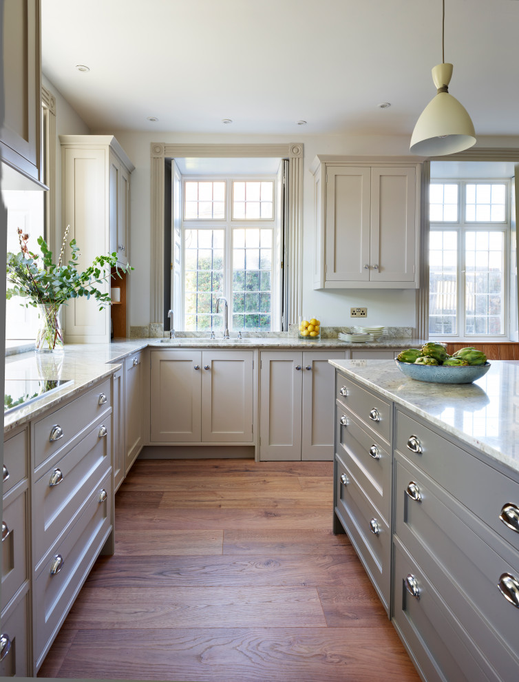 Inspiration for a large timeless eat-in kitchen remodel in Buckinghamshire with an integrated sink, shaker cabinets, granite countertops, gray backsplash, black appliances, an island and white countertops