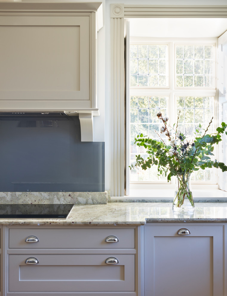 Foto di una grande cucina tradizionale con lavello integrato, ante in stile shaker, top in granito, paraspruzzi grigio, elettrodomestici neri e top bianco