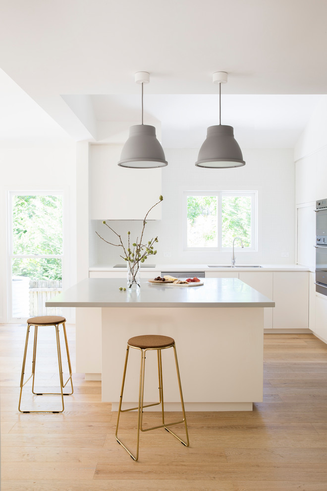 Esempio di una cucina design con lavello a doppia vasca, ante lisce, ante bianche, elettrodomestici in acciaio inossidabile, parquet chiaro e pavimento beige