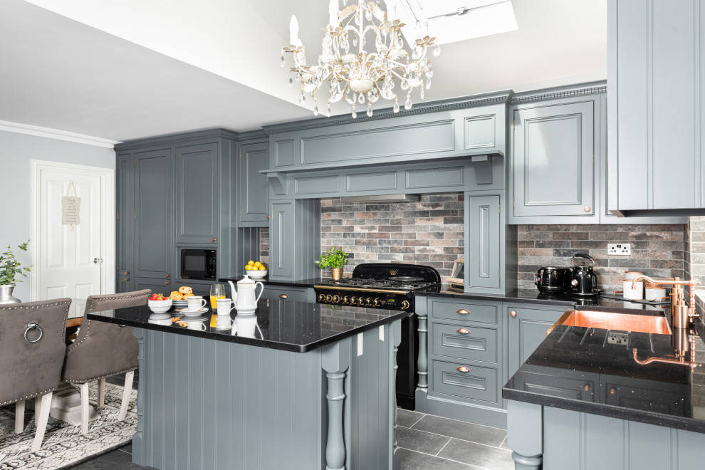 This is an example of a medium sized traditional l-shaped kitchen/diner in Dorset with beaded cabinets, grey cabinets, quartz worktops, stone tiled splashback, an island and black worktops.