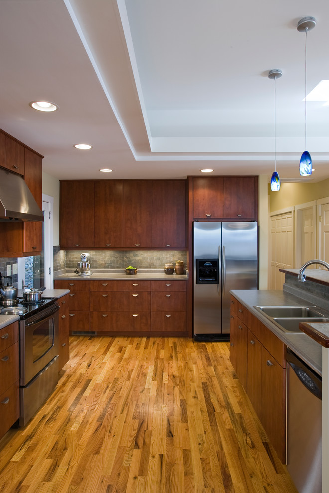 Inspiration for a timeless u-shaped kitchen remodel in Other with stainless steel appliances, a double-bowl sink, flat-panel cabinets, dark wood cabinets and gray backsplash
