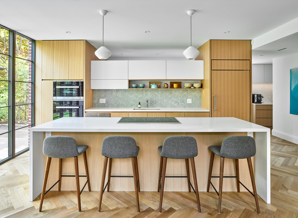 Example of a trendy light wood floor kitchen design in Toronto with an undermount sink, flat-panel cabinets, white cabinets, green backsplash, paneled appliances, an island and white countertops