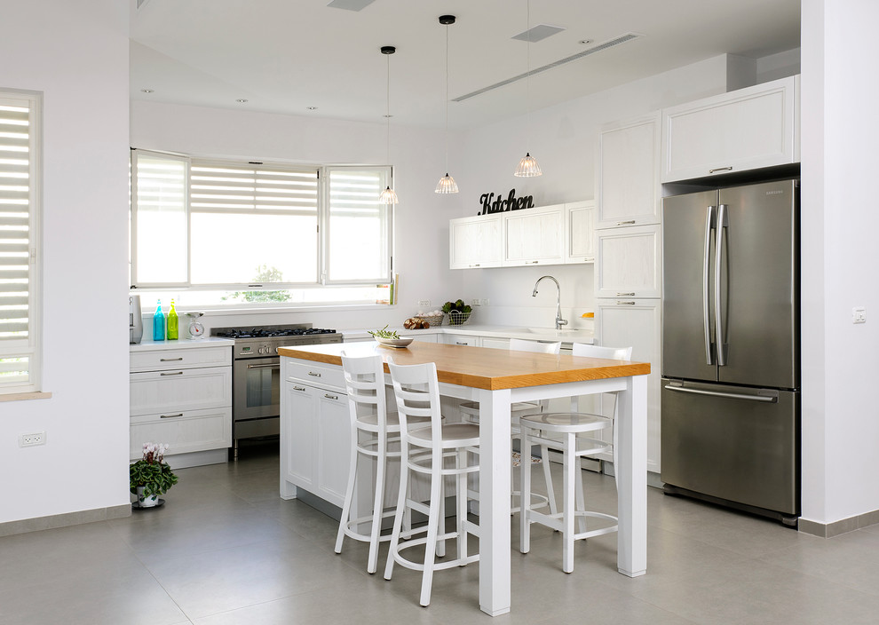 Moderne Küche in L-Form mit Arbeitsplatte aus Holz, Schrankfronten mit vertiefter Füllung, weißen Schränken und Küchengeräten aus Edelstahl in Tel Aviv