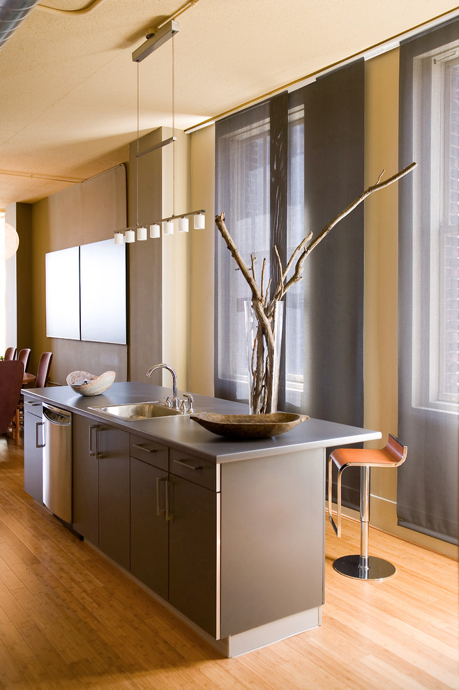 Moderne Küche mit Einbauwaschbecken, flächenbündigen Schrankfronten, braunen Schränken, Edelstahl-Arbeitsplatte, braunem Holzboden und Kücheninsel in Cincinnati