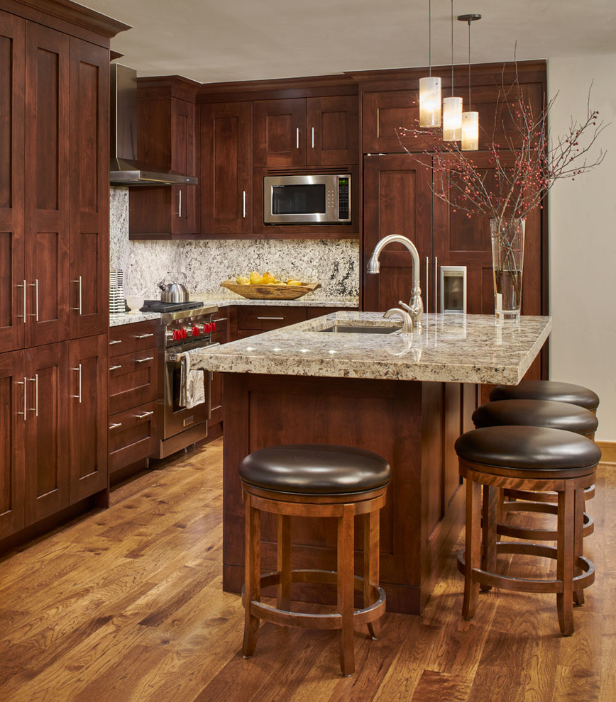 Eat-in kitchen - modern l-shaped medium tone wood floor eat-in kitchen idea in Denver with a double-bowl sink, beaded inset cabinets, dark wood cabinets, granite countertops, beige backsplash, stone tile backsplash, stainless steel appliances and an island
