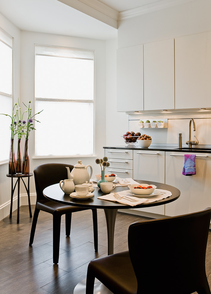 Пример оригинального дизайна: кухня в стиле модернизм с обеденным столом, плоскими фасадами, белыми фасадами и эркером