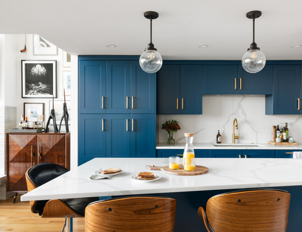 Foto på ett mellanstort vintage vit kök, med en undermonterad diskho, skåp i shakerstil, blå skåp, bänkskiva i kvarts, vitt stänkskydd, stänkskydd i sten, rostfria vitvaror, ljust trägolv, en köksö och brunt golv