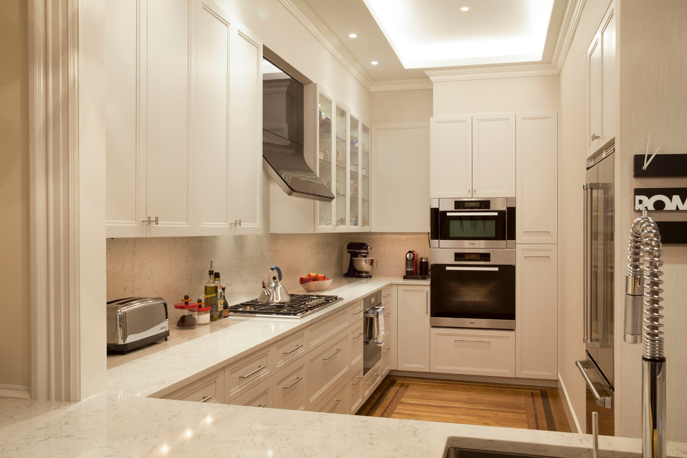 This is an example of a classic u-shaped enclosed kitchen in Boston with a submerged sink, recessed-panel cabinets, white cabinets and stainless steel appliances.