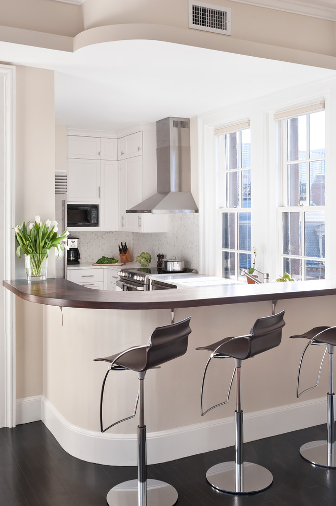 Example of a transitional u-shaped enclosed kitchen design in Boston with stainless steel appliances, white cabinets and white backsplash