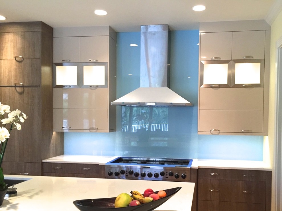 Diseño de cocina lineal actual abierta con salpicadero de vidrio templado, electrodomésticos de acero inoxidable, una isla y salpicadero azul