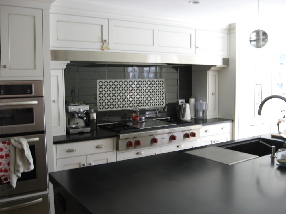 Moderne Wohnküche mit flächenbündigen Schrankfronten, weißen Schränken, Granit-Arbeitsplatte, Küchenrückwand in Schwarz, Rückwand aus Glasfliesen und Kücheninsel in New York