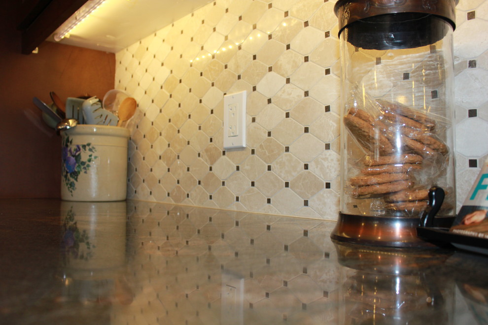 Aménagement d'une cuisine classique en bois brun avec un placard avec porte à panneau encastré, plan de travail en marbre, une crédence beige et une crédence en carrelage de pierre.
