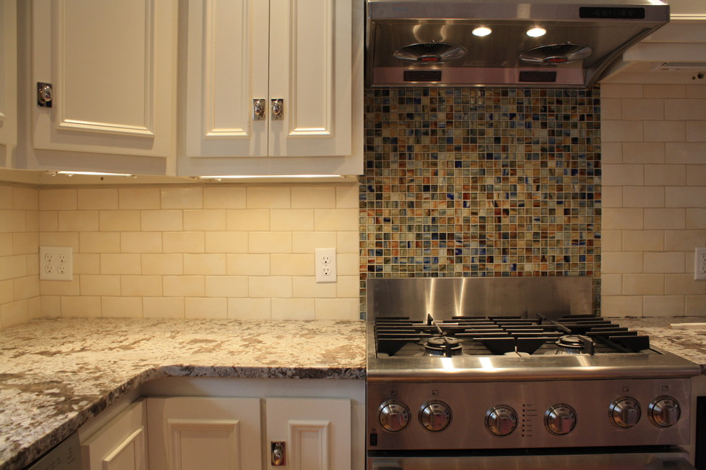 Example of a classic eat-in kitchen design in Burlington with flat-panel cabinets, white cabinets, granite countertops, multicolored backsplash, ceramic backsplash and stainless steel appliances