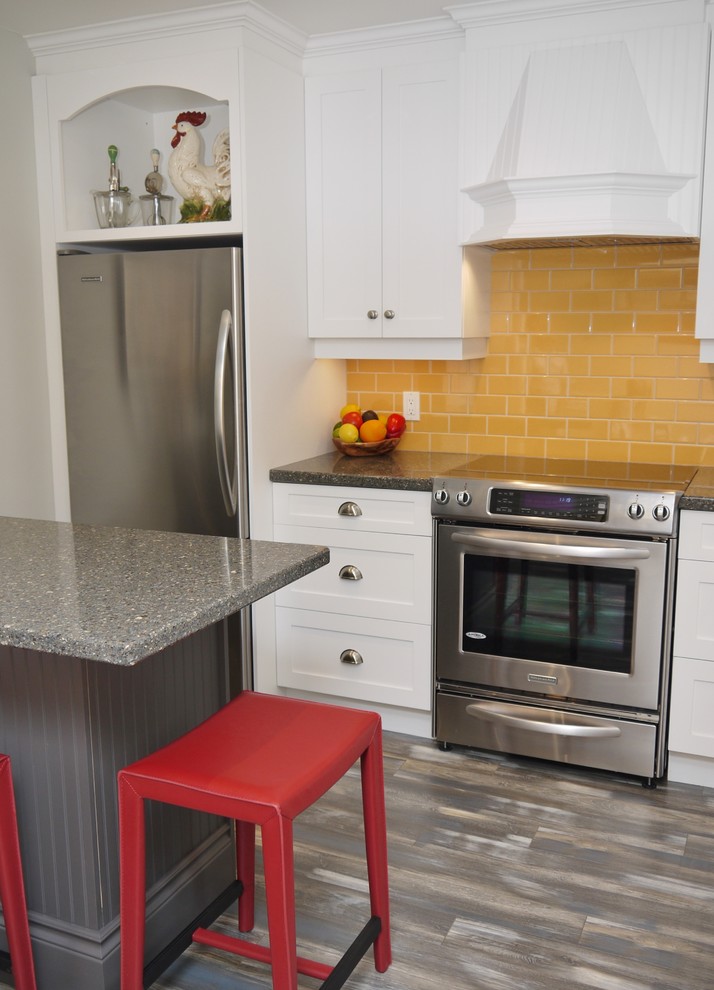 Foto på ett avskilt, mellanstort lantligt l-kök, med en rustik diskho, luckor med infälld panel, vita skåp, bänkskiva i kvarts, gult stänkskydd, stänkskydd i porslinskakel, rostfria vitvaror och en köksö