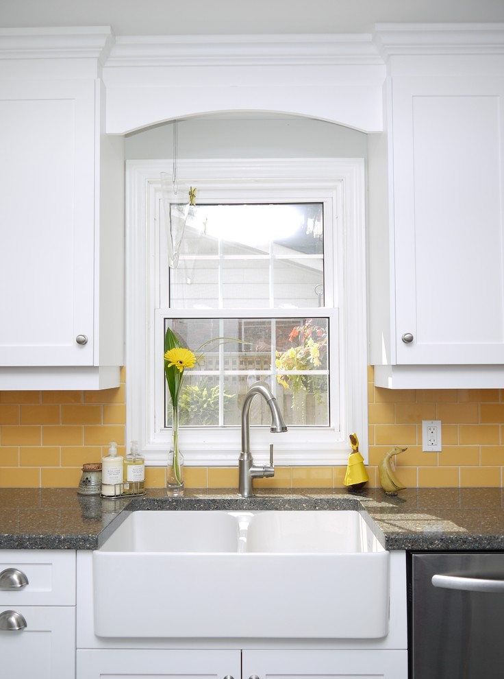 Bild på ett avskilt, mellanstort lantligt l-kök, med en rustik diskho, luckor med infälld panel, vita skåp, bänkskiva i kvarts, gult stänkskydd, stänkskydd i porslinskakel, rostfria vitvaror och en köksö