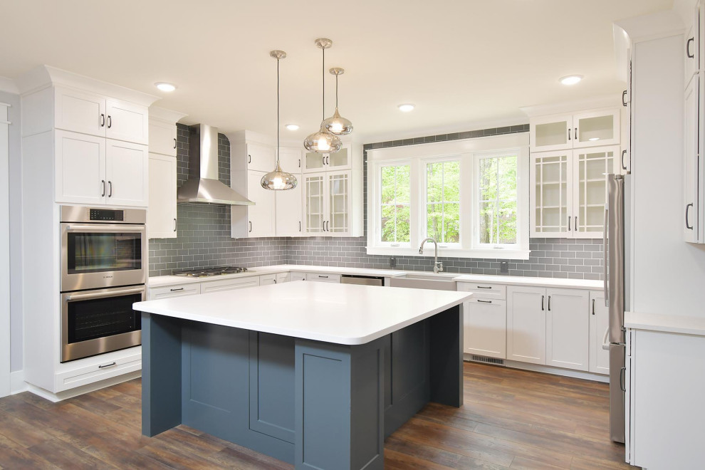 Design ideas for a large traditional u-shaped open plan kitchen in Raleigh with a submerged sink, shaker cabinets, white cabinets, engineered stone countertops, grey splashback, ceramic splashback, stainless steel appliances, vinyl flooring, an island, brown floors and white worktops.