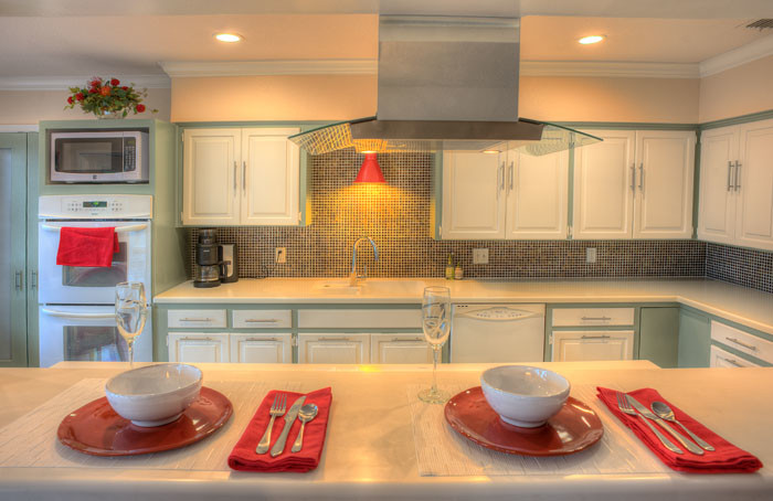 Modern inredning av ett mellanstort kök, med luckor med infälld panel, gröna skåp, bänkskiva i kvartsit, stänkskydd med metallisk yta, stänkskydd i glaskakel, vita vitvaror och travertin golv