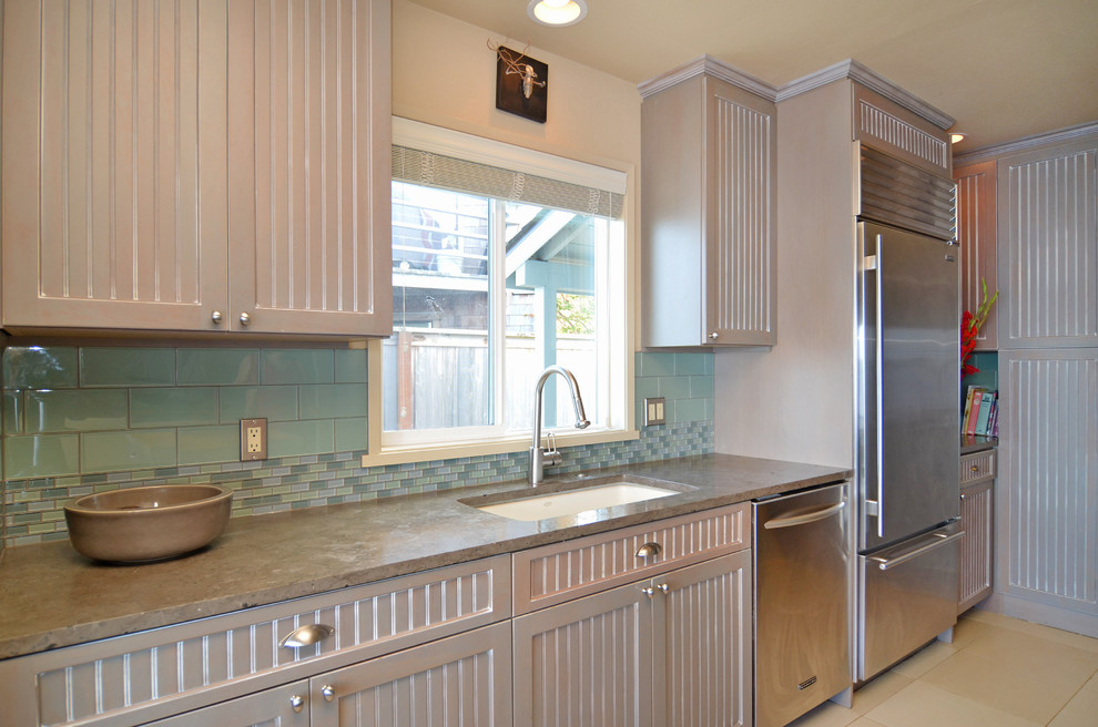 Cette image montre une cuisine américaine marine en U avec un évier encastré, un placard à porte affleurante, des portes de placard marrons et un plan de travail en granite.