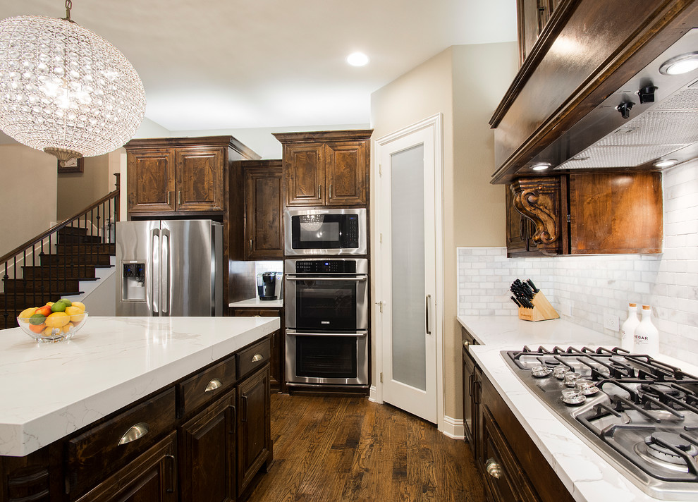 Example of a large transitional u-shaped medium tone wood floor and brown floor eat-in kitchen design in Dallas with a farmhouse sink, raised-panel cabinets, dark wood cabinets, quartz countertops, gray backsplash, marble backsplash, stainless steel appliances, an island and white countertops