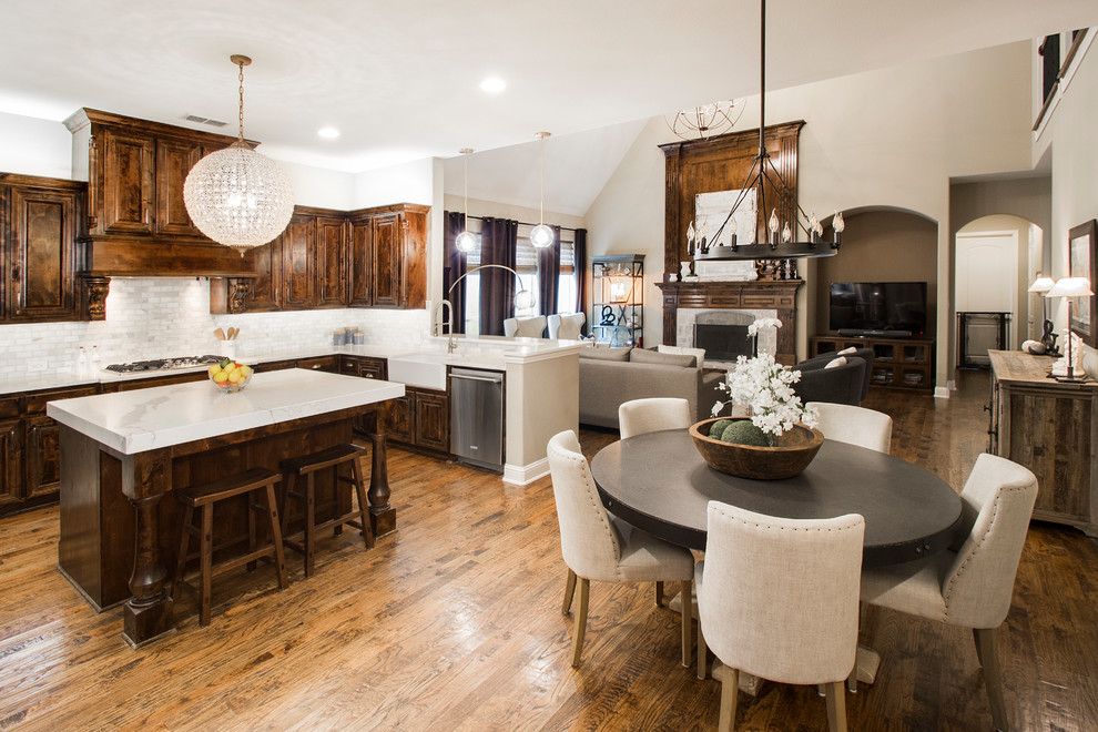 Inspiration for a large transitional u-shaped medium tone wood floor and brown floor eat-in kitchen remodel in Dallas with a farmhouse sink, raised-panel cabinets, dark wood cabinets, quartz countertops, gray backsplash, marble backsplash, stainless steel appliances, an island and white countertops