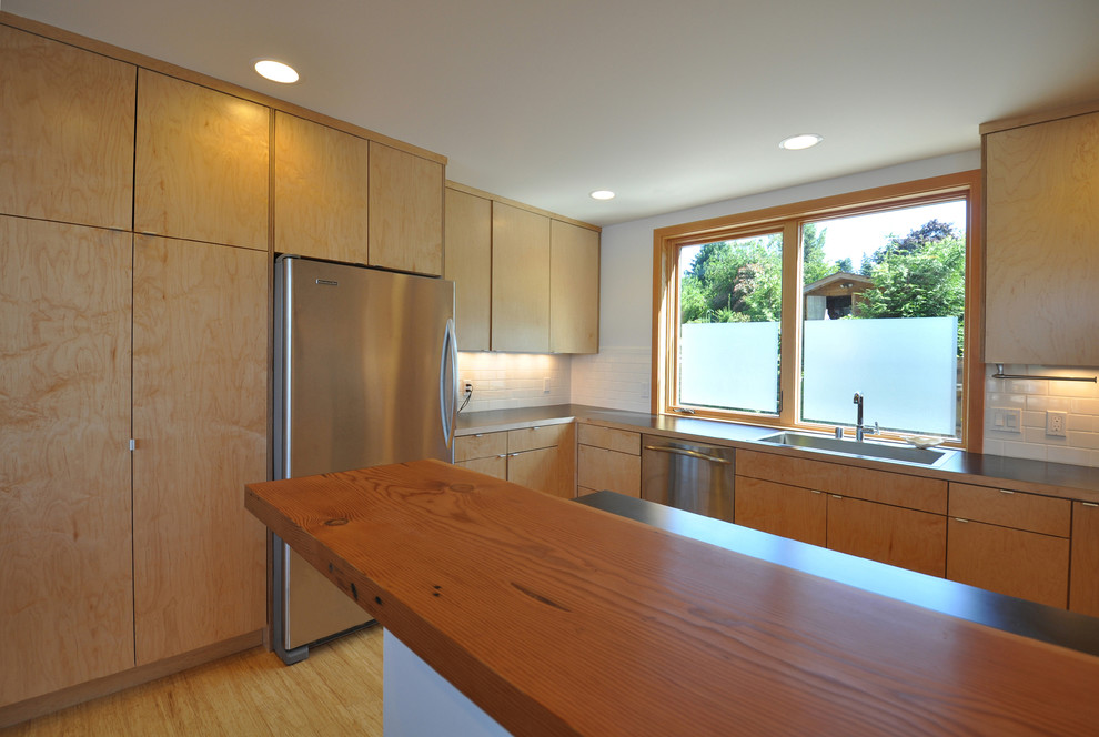 Inspiration for a small contemporary u-shaped bamboo floor open concept kitchen remodel in Seattle with a drop-in sink, flat-panel cabinets, light wood cabinets, wood countertops, white backsplash, subway tile backsplash and stainless steel appliances