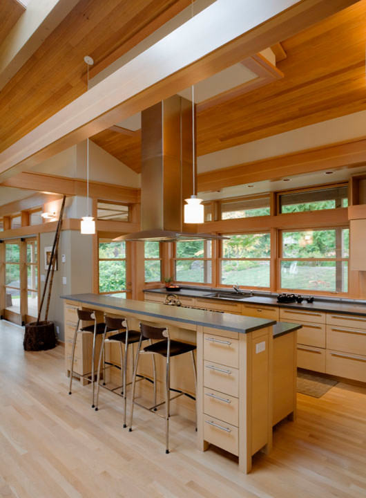 Inspiration for a mid-sized asian l-shaped light wood floor and beige floor open concept kitchen remodel in Seattle with an undermount sink, flat-panel cabinets, light wood cabinets, solid surface countertops, stainless steel appliances, an island and window backsplash