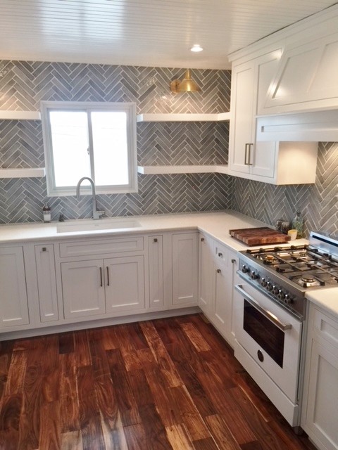 Modern inredning av ett litet kök, med en enkel diskho, skåp i shakerstil, vita skåp, bänkskiva i kvarts, grått stänkskydd, stänkskydd i terrakottakakel, vita vitvaror, mellanmörkt trägolv och brunt golv