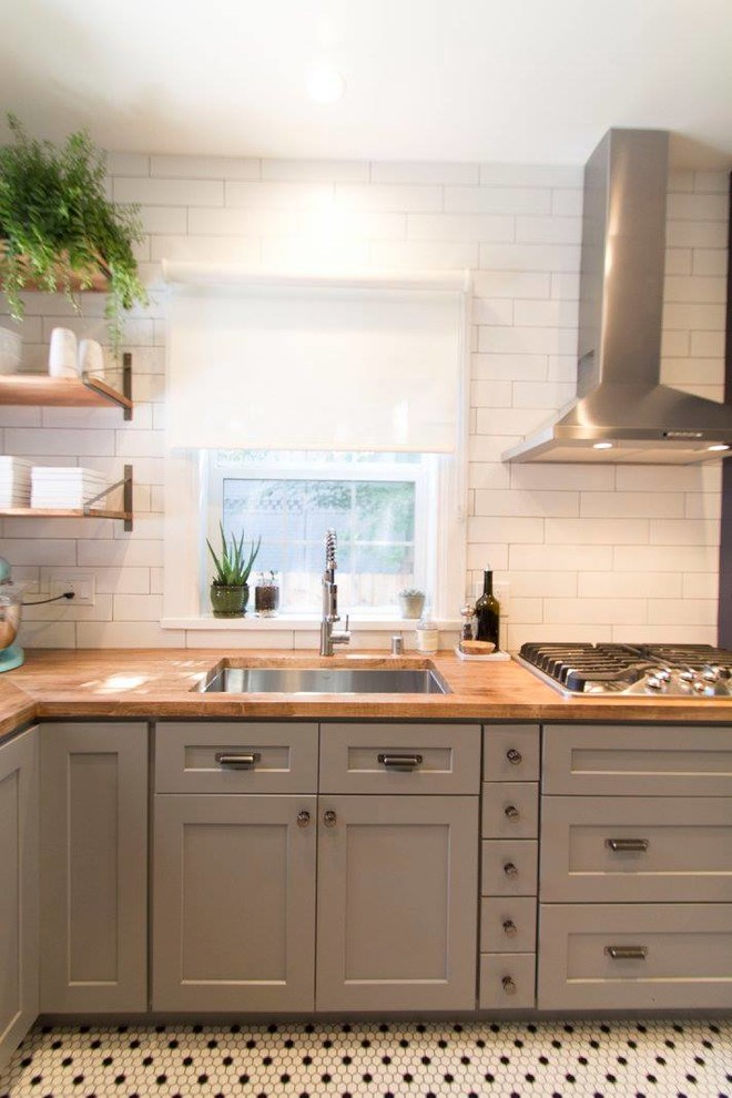 Example of a mid-sized 1960s galley ceramic tile and white floor eat-in kitchen design in Denver with an undermount sink, shaker cabinets, gray cabinets, wood countertops, white backsplash, ceramic backsplash, stainless steel appliances and a peninsula