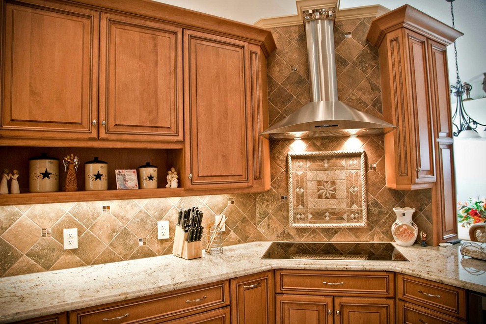 Klassisk inredning av ett kök, med en undermonterad diskho, luckor med upphöjd panel, granitbänkskiva, stänkskydd i stenkakel och rostfria vitvaror