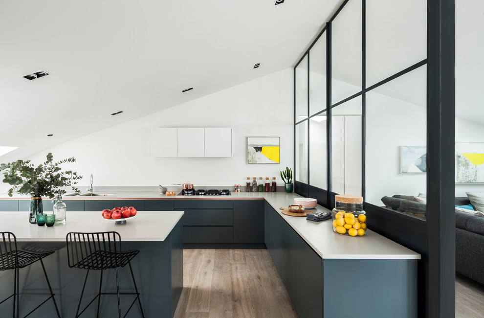 Immagine di una cucina minimal di medie dimensioni con top in superficie solida, elettrodomestici in acciaio inossidabile e parquet chiaro