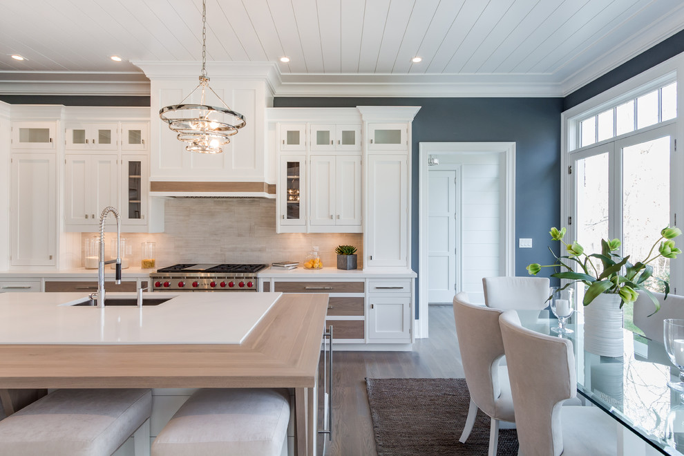 Inspiration for a large traditional l-shaped kitchen/diner in New York with white cabinets, engineered stone countertops, beige splashback, stainless steel appliances, dark hardwood flooring and an island.