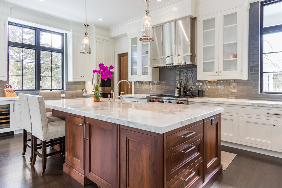 Inspiration for a large transitional u-shaped dark wood floor kitchen remodel in Other with a farmhouse sink, white cabinets, marble countertops, gray backsplash, subway tile backsplash, stainless steel appliances, an island and recessed-panel cabinets