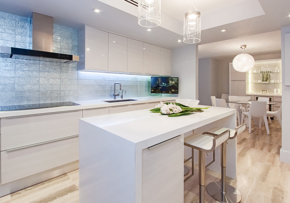 Inspiration for a medium sized modern galley kitchen/diner in Miami with a built-in sink, flat-panel cabinets, white cabinets, engineered stone countertops, blue splashback, metro tiled splashback, stainless steel appliances, travertine flooring and an island.