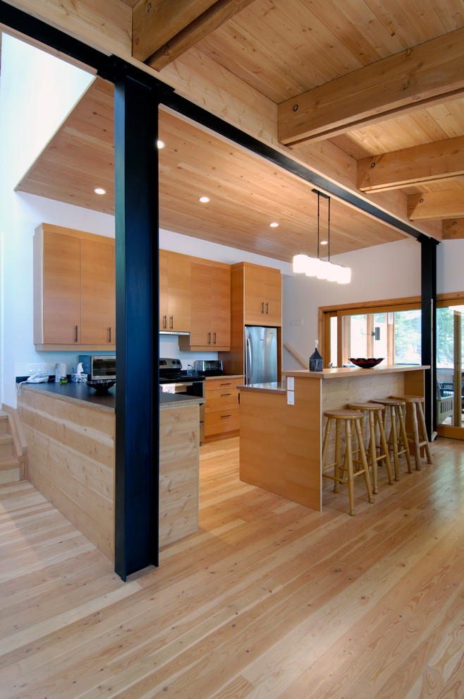 Exempel på ett stort modernt kök, med släta luckor, rostfria vitvaror, ljust trägolv och en köksö