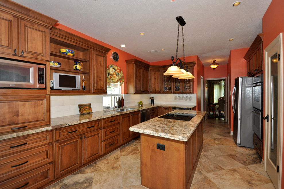 Example of a large classic l-shaped enclosed kitchen design in Houston with a double-bowl sink, raised-panel cabinets, medium tone wood cabinets, white backsplash, stainless steel appliances and an island