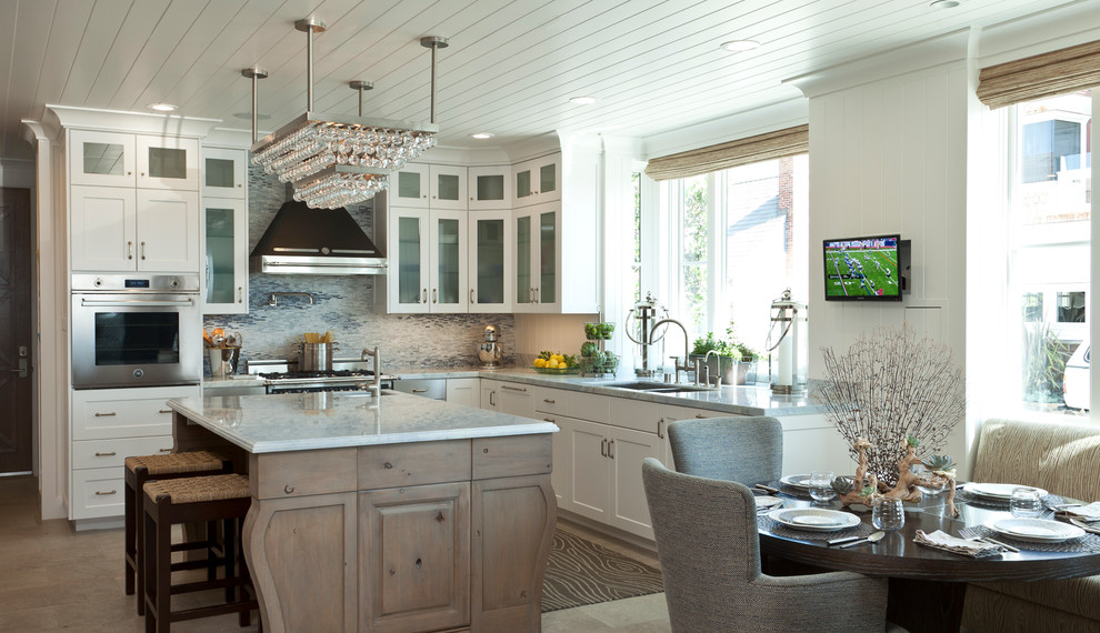 Foto på ett maritimt kök, med stänkskydd i mosaik, en undermonterad diskho, luckor med glaspanel, vita skåp, bänkskiva i kvartsit, blått stänkskydd och rostfria vitvaror