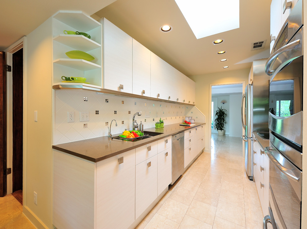Photo of a large modern galley enclosed kitchen in Austin with a double-bowl sink, flat-panel cabinets, white cabinets, composite countertops, white splashback, mosaic tiled splashback, stainless steel appliances, travertine flooring, no island and beige floors.