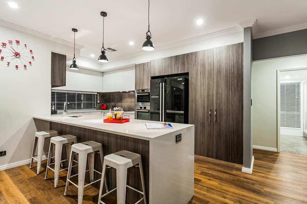 Contemporary u-shaped kitchen in Perth with flat-panel cabinets, dark wood cabinets, brown splashback, stainless steel appliances, medium hardwood flooring and a breakfast bar.