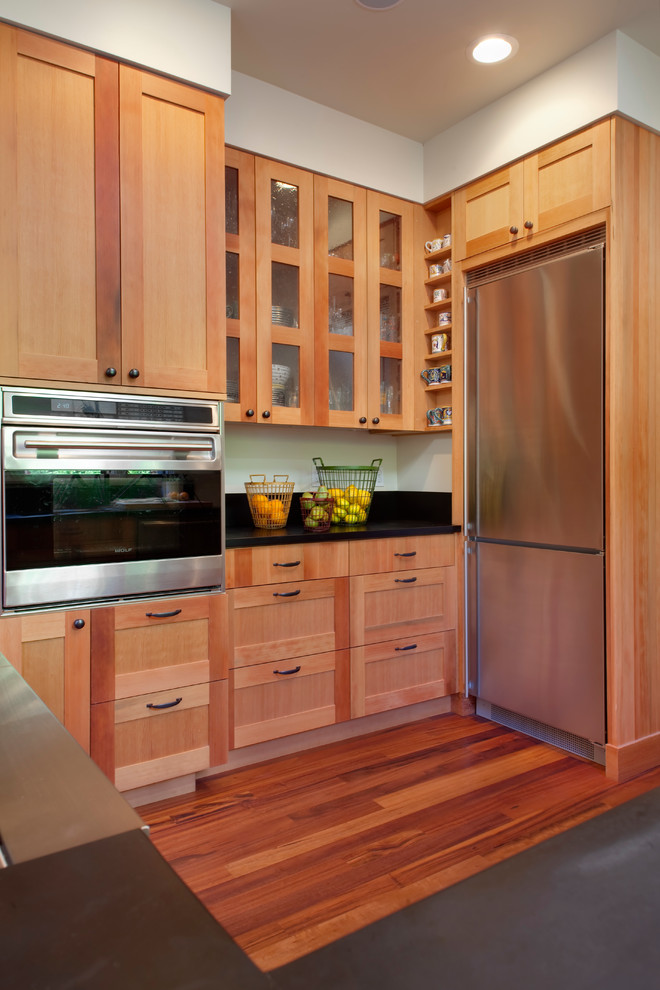 Exempel på ett modernt u-kök, med en undermonterad diskho, luckor med infälld panel, svart stänkskydd, rostfria vitvaror och mellanmörkt trägolv