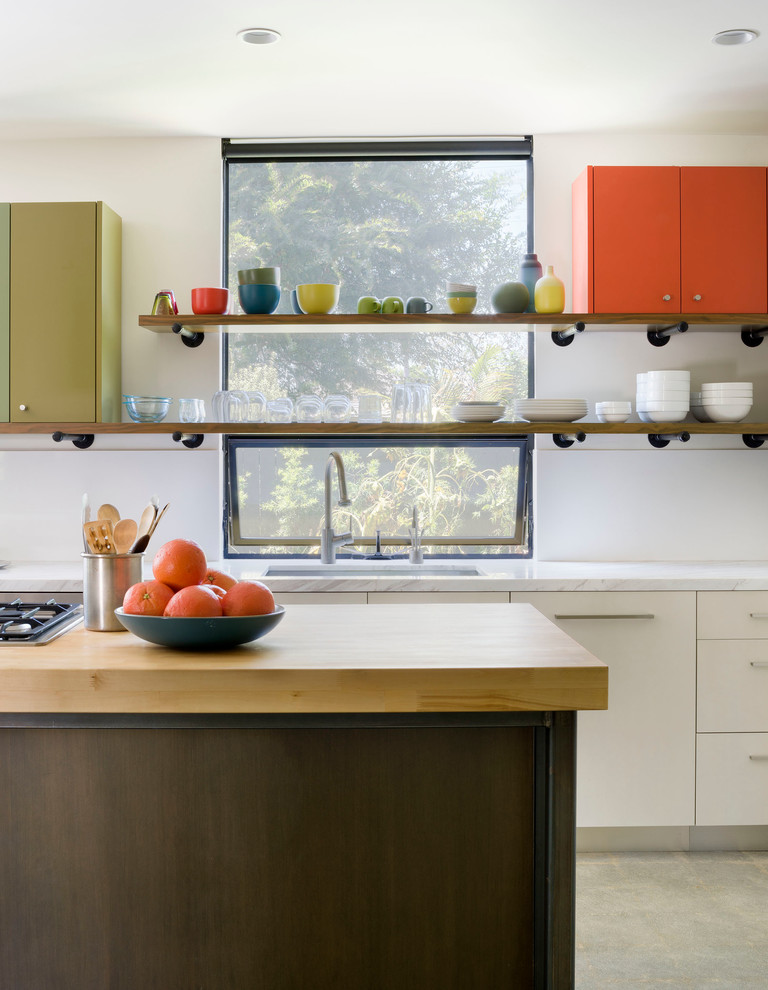 Exempel på ett litet modernt kök, med en undermonterad diskho, släta luckor, skåp i ljust trä, marmorbänkskiva, vitt stänkskydd, stänkskydd i sten, rostfria vitvaror, betonggolv och en köksö