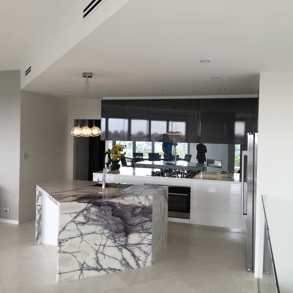 Exempel på ett stort modernt kök, med en nedsänkt diskho, släta luckor, vita skåp, marmorbänkskiva, spegel som stänkskydd, rostfria vitvaror, klinkergolv i porslin och en köksö