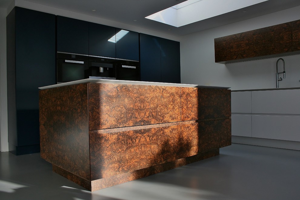 This is an example of a medium sized contemporary l-shaped kitchen/diner in London with a submerged sink, flat-panel cabinets, blue cabinets, engineered stone countertops, black appliances, concrete flooring and an island.