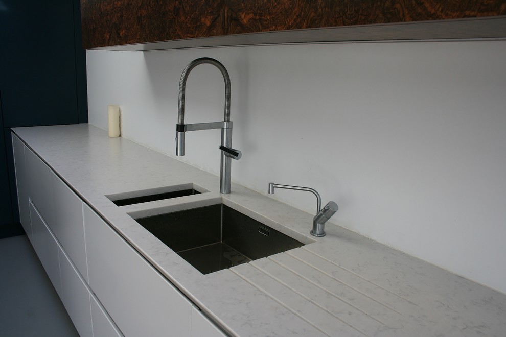 Immagine di una cucina contemporanea di medie dimensioni con lavello sottopiano, ante lisce, ante bianche, top in quarzo composito, elettrodomestici in acciaio inossidabile e pavimento in cemento