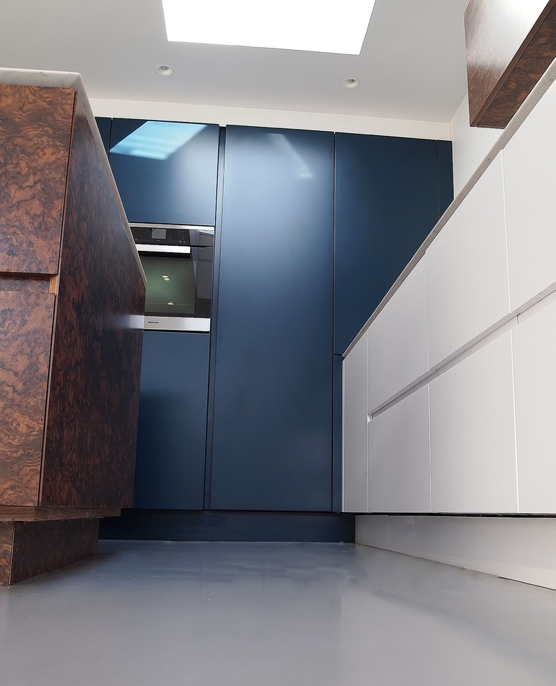 Medium sized contemporary l-shaped kitchen/diner in London with flat-panel cabinets, blue cabinets, engineered stone countertops, stainless steel appliances and an island.